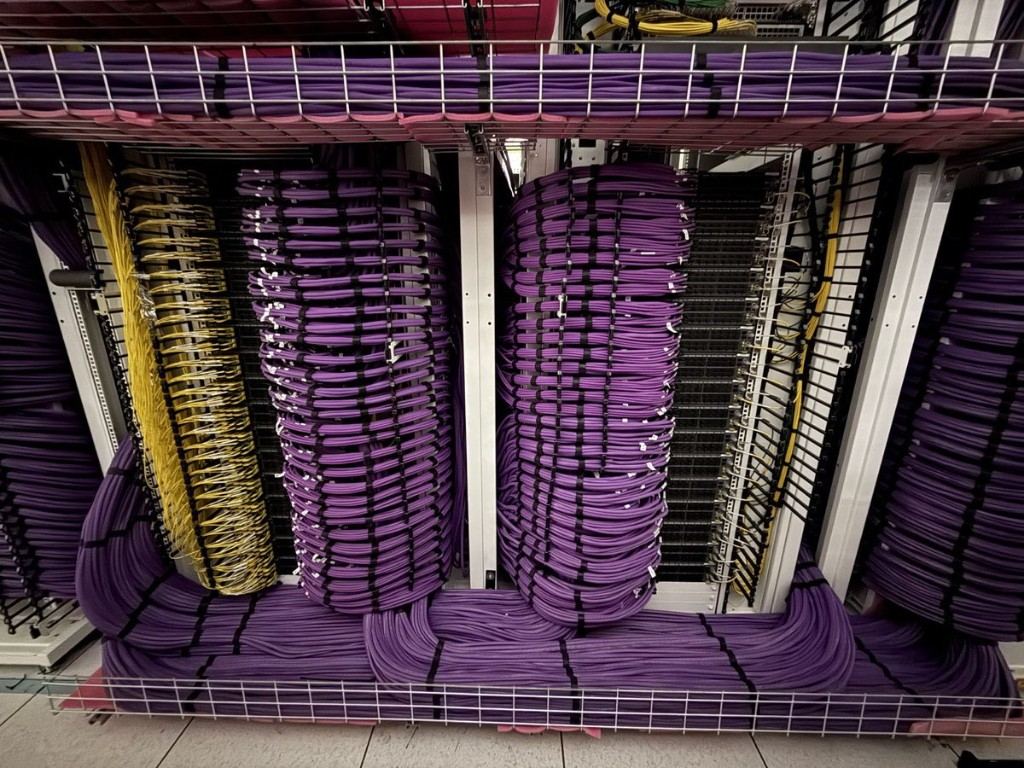 Overhead cable containment and busway in a data hall under
                    construction, with tiered basket tray carrying fibre and power